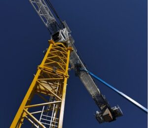 Yellow tower crane and blue boom lift against a clear sky.