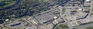 Aerial view of a suburban shopping center with multiple large parking lots and surrounding roads.