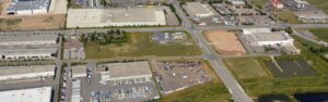 Aerial view of an industrial park with large warehouses, parking lots, and a multi-road intersection forming a crossroads.