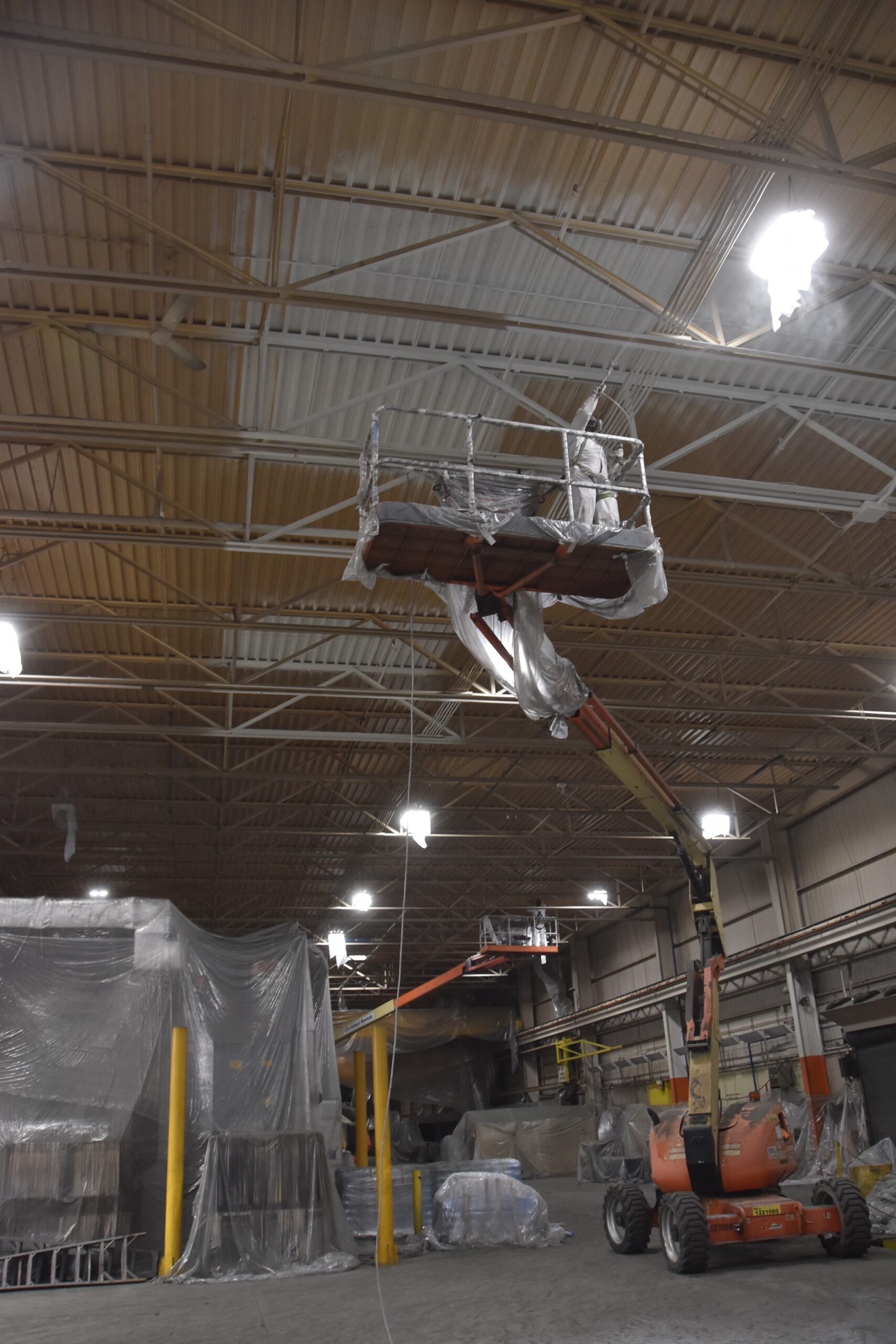 BEST Painting crew spraying plant ceiling from boom lift