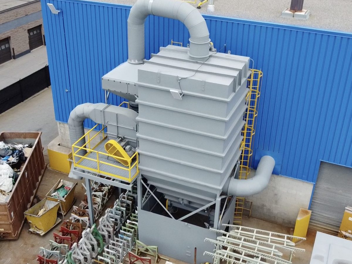 Industrial dust collector with ductwork and access ladder beside a blue plant wall in Ontario