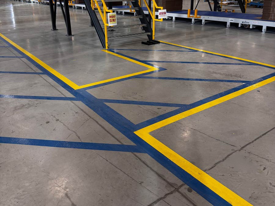 Warehouse floor with blue and yellow safety markings around a staircase and aisles.