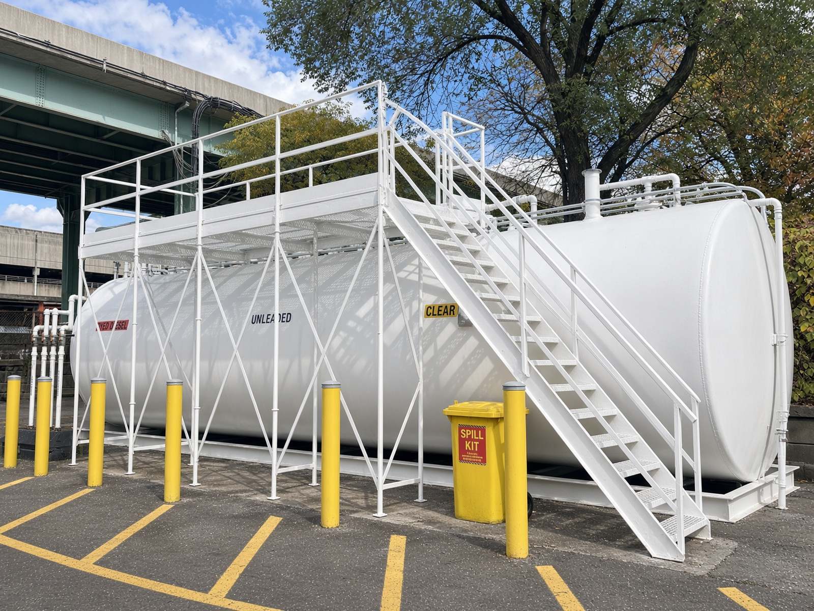 White above-ground diesel and unleaded fuel tank with access platform, stairs, yellow bollards and spill kit after exterior painting