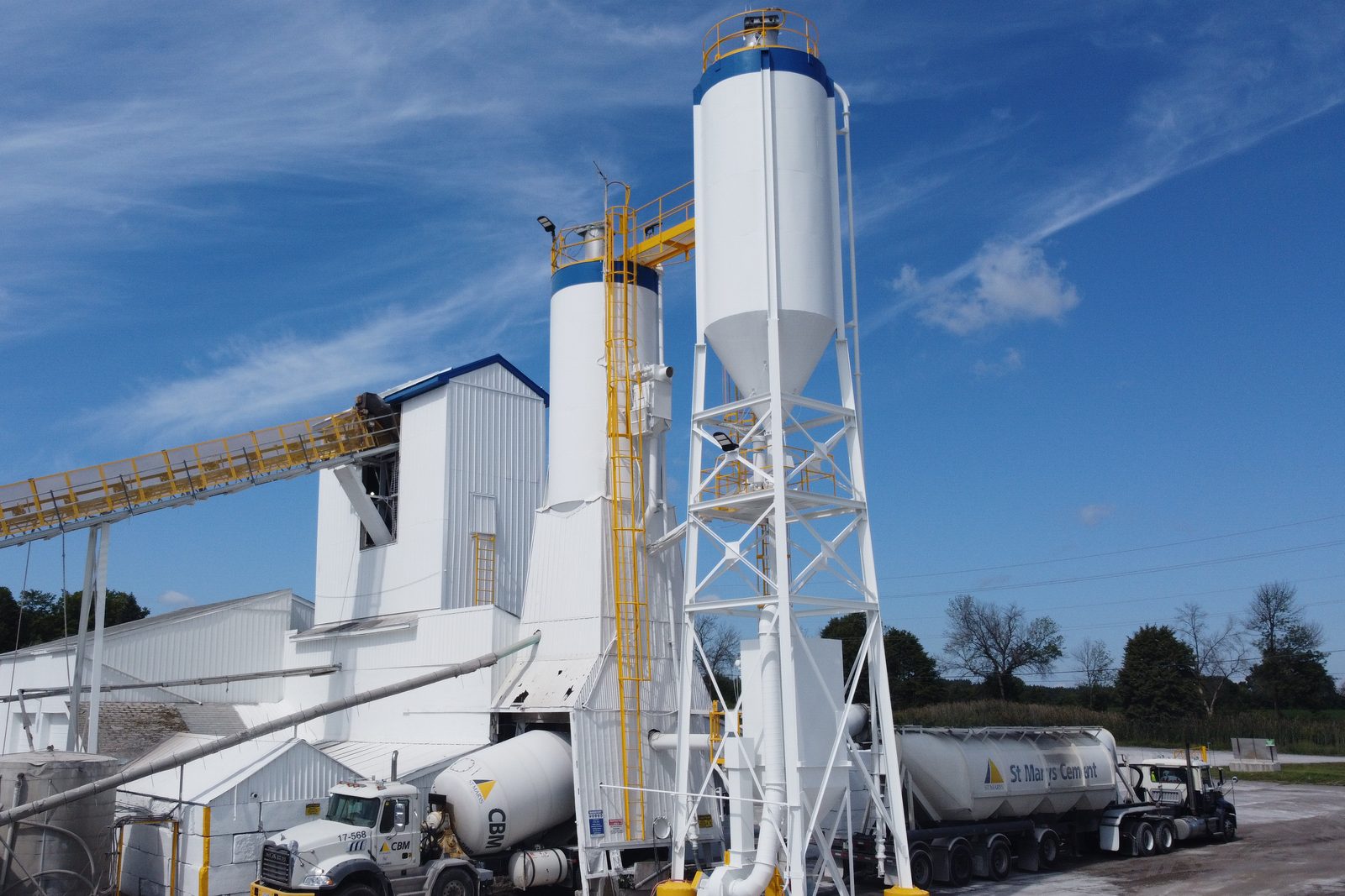 White concrete batch plant with painted silos and a steel support tower at an industrial plant