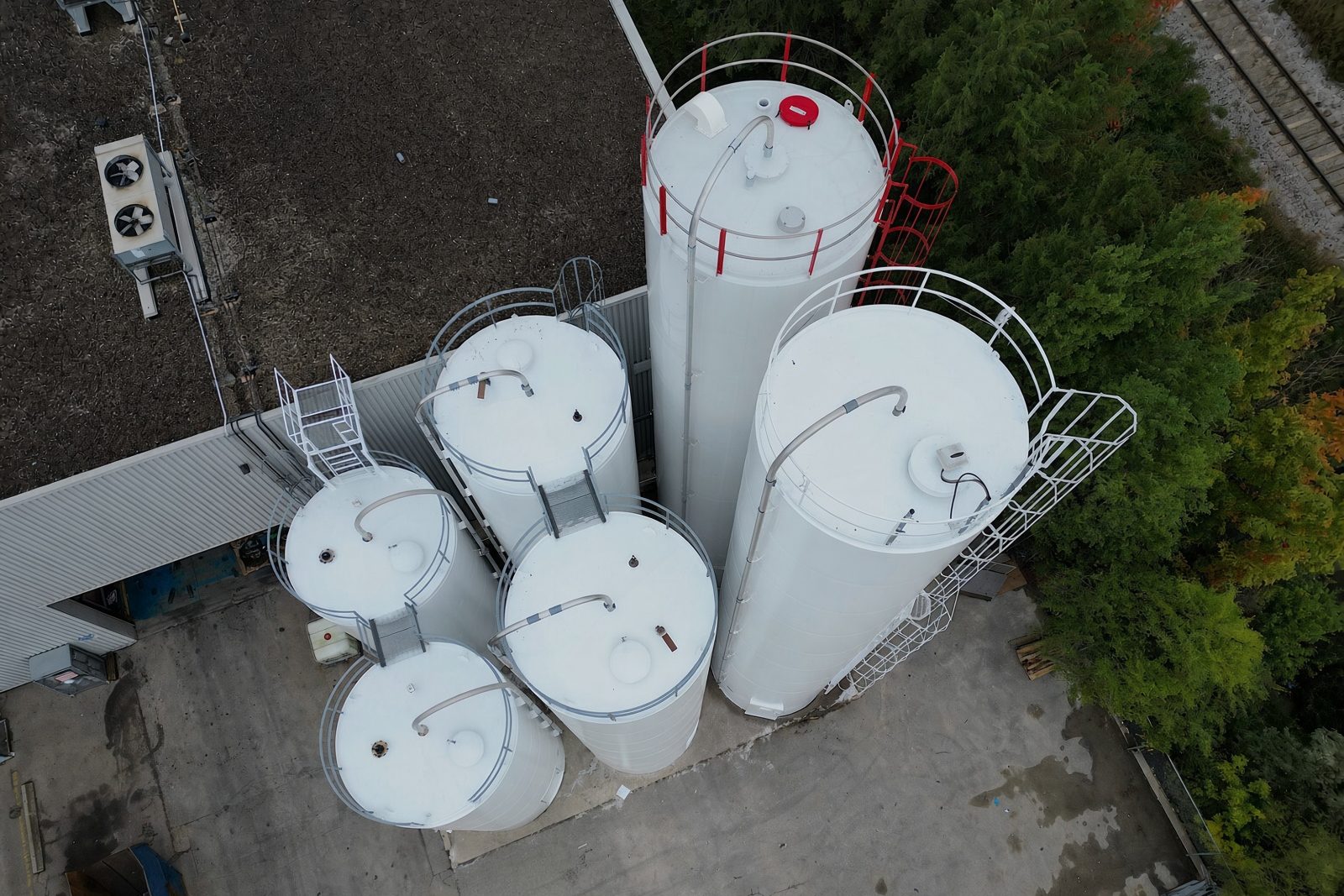 Aerial view of white painted silos with safety cages and ladders