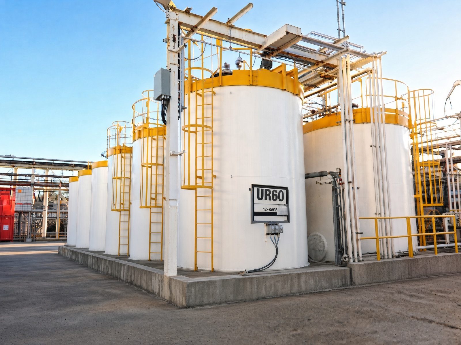 White vertical process tanks with yellow caged ladders and access platforms after exterior painting