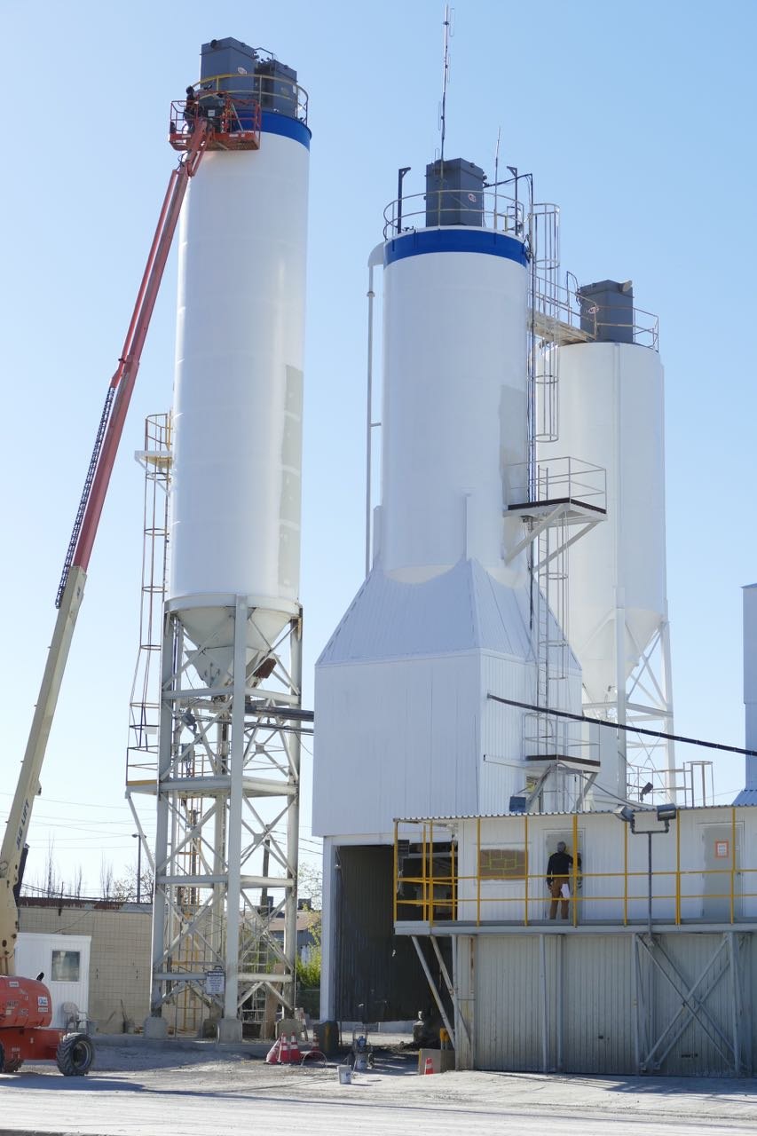 Freshly painted white industrial silos with a boom-lift crew at the top, BEST Painting